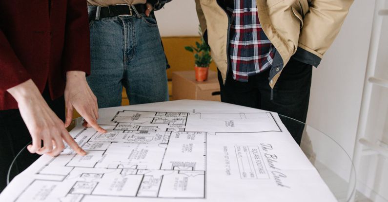 Property Selling - Three People Standing Near Blueprint on Glass Table